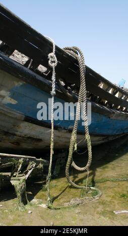 Rope draped over the side of an old, rotten boat. Stock Photo