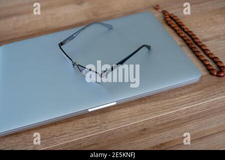 Silver laptop and eye glasses on the table Stock Photo