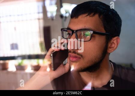Guy talking on the phone while looking from window glass Stock Photo