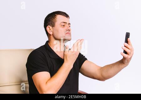 Senior man in a chair shows with gestures a sign, please, communicating via video communication. White background and empty side space. Stock Photo