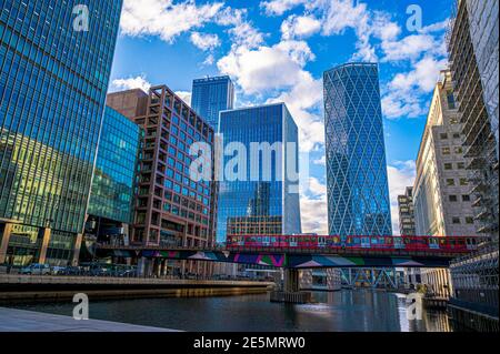 London, England, UK - January 22, 2021: Bridge architecture and a red overground in front of the Financial buildings in the Canary Wharf area Stock Photo
