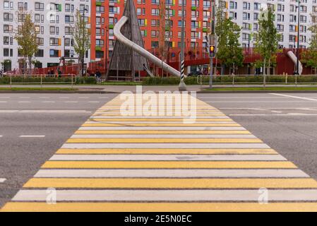 Pedestrian crosswalk across the road. A wide zebra crossing across the street. Yellow-white transition in Russia. Stock Photo