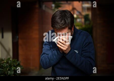 PICTURE POSED BY MODEL File photo dated 14/03/20 of a man sneezing into a tissue. The number of days British workers took off sick fell to the lowest in over a quarter of a century last year suggesting a problem with presenteeism, according to a new report. Issue date: Thursday January 28, 2021. Stock Photo