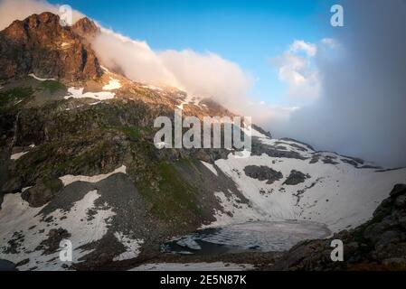 Beautiful alpine second lake Klukhor, under a layer of ice and snow on the border of Russia and Abkhazia Stock Photo