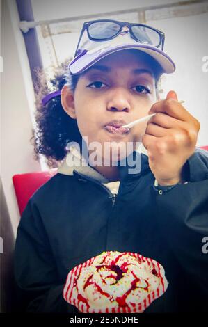 young girl tastes a very good and tasty ice cream with cream, berries jelly and candies Stock Photo