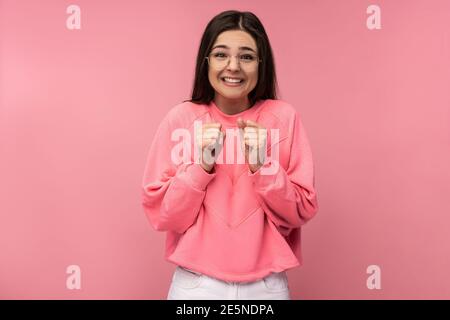 Photo of attractive young woman in glasses waits impatiently, looks forward. Wears casual pink t-shirt isolated pink color background Stock Photo
