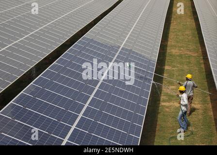 Workers clean photovoltaic panels inside a solar power plant in Gujarat, India, July 2, 2015. India's $100 billion push into solar energy over the next decade will be driven by foreign players as uncompetitive local manufacturers fall by the wayside, no longer protected by government restrictions on the sector. REUTERS/Amit Dave