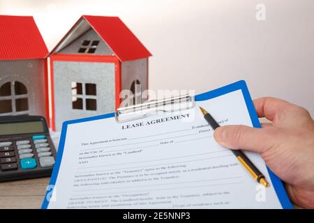 The agent holds the form of the real estate lease, house models, calculator. Stock Photo