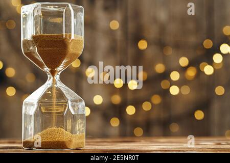 Hourglass on wooden desk against blurred lights Stock Photo