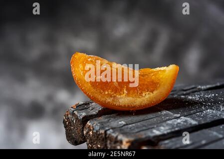 a piece of spanish candied orange on a rustic dark gray wooden surface, against a gray background Stock Photo