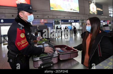 Shanghai, China. 28th Jan, 2021. Policeman Zhou Qiang (L) conducts security check at Hongqiao Railway Station in Shanghai, east China, Jan. 28, 2021. China kicked off its annual travel rush, known as 'chunyun,' on Thursday, with hundreds of millions starting to head home for the Spring Festival that falls on Feb. 12 this year. Known as the world's largest annual human migration, the travel rush lasts 40 days from Jan. 28 to March 8 this year. Credit: Fan Jun/Xinhua/Alamy Live News Stock Photo