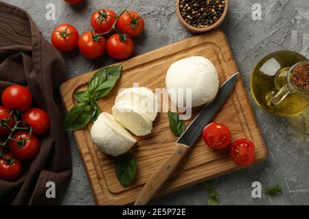 Concept of tasty eating with mozzarella on board on gray table Stock Photo