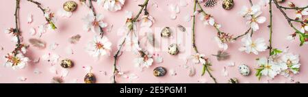Easter holiday background. Flat-lay of tender Spring almond blossom flowers on branches, feathers, quail eggs over light pink background. Greeting card concept Stock Photo