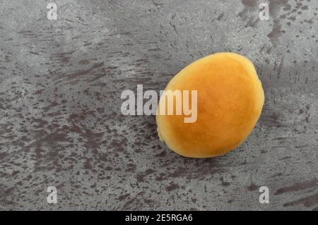 Top view of a single fresh homemade yeast roll on a gray background. Stock Photo