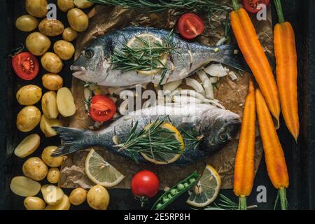 Grilled dorado fish with aromatic herbs, spices and vegetables. Healthy sea food for diet, top view Stock Photo