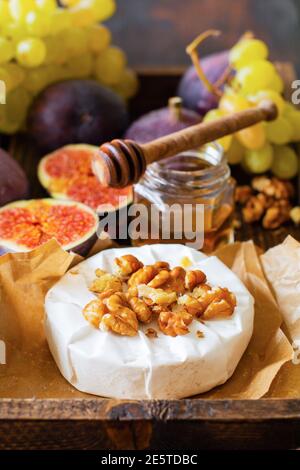 Vintage retro concept. Blue cheese with figs, walnuts, honey and thyme served for a dinner in dark key on wooden background in retro style. Selective Stock Photo