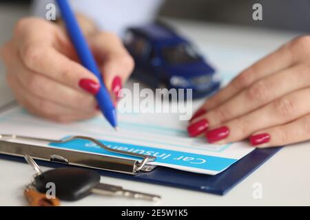 Agent filling out car insurance documents with pen Stock Photo