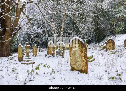 Graveyard and tombstones in St John's Church near Woking, Diocese of Guildford, Surrey, south-east England after a heavy snowfall in winter Stock Photo