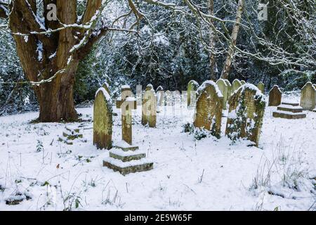 Graveyard and tombstones in St John's Church near Woking, Diocese of Guildford, Surrey, south-east England after a heavy snowfall in winter Stock Photo