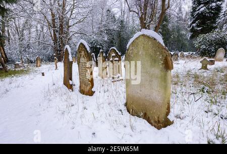 Graveyard and tombstones in St John's Church near Woking, Diocese of Guildford, Surrey, south-east England after a heavy snowfall in winter Stock Photo