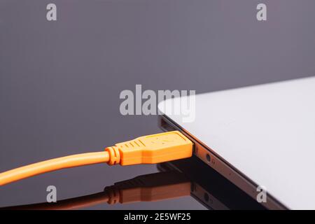 laptop with USB orange cable. Stock Photo
