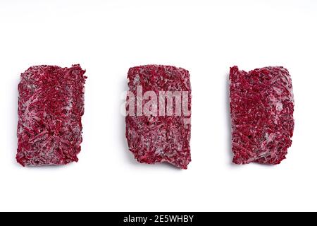 Bricks of frozen grated beets. Procurement of frozen food. Semifinished. Stock Photo