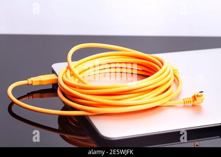 laptop with USB orange rolled cable. Stock Photo