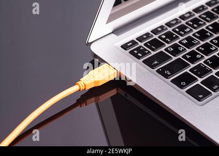laptop with USB orange cable. Stock Photo
