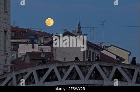 Milan, People stroll at sunset and full moon on the Naviglio Grande Editorial Usage Only Stock Photo