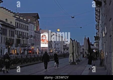 Milan, People stroll at sunset and full moon on the Naviglio Grande Editorial Usage Only Stock Photo