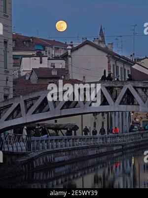 Milan, People stroll at sunset and full moon on the Naviglio Grande Editorial Usage Only Stock Photo