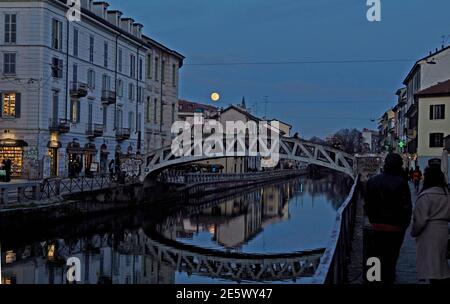 Milan, People stroll at sunset and full moon on the Naviglio Grande Editorial Usage Only Stock Photo