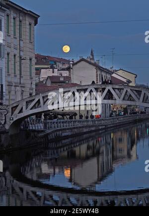 Milan, People stroll at sunset and full moon on the Naviglio Grande Editorial Usage Only Stock Photo