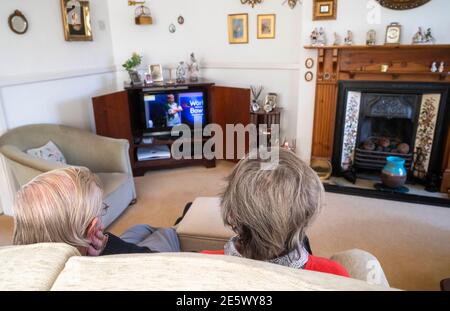 Elderly couple in their 80s watching bowls on television in their sitting room during lockdown   Photograph taken by Simon Dack Stock Photo