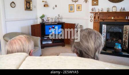 Elderly couple in their 80s watching bowls on television in their sitting room during lockdown   Photograph taken by Simon Dack Stock Photo