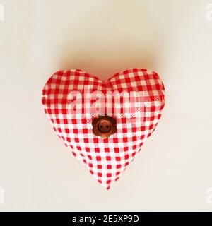 Handmade heart made of checkered fabric with a button flower in the middle on a beige background with a copy space Stock Photo