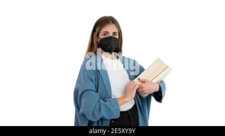 Portrait of a female student or college girl with a black mask and several books on her arm. Concept of studies during the Covid 19 or Coronavirus pan Stock Photo