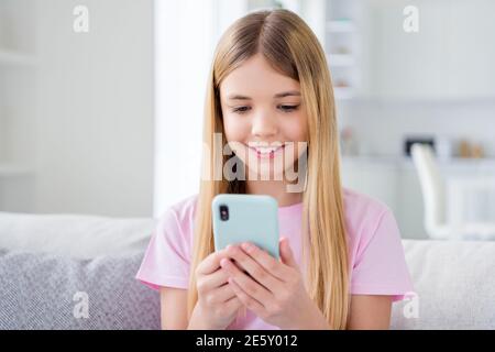 Close up photo of positive small kid girl study remote rest relax use smartphone follow share repost quarantine stay home information sit comfort Stock Photo