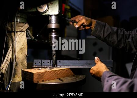 Stock photo of anonymous worker using drilling machine for metal in his workshop. Stock Photo