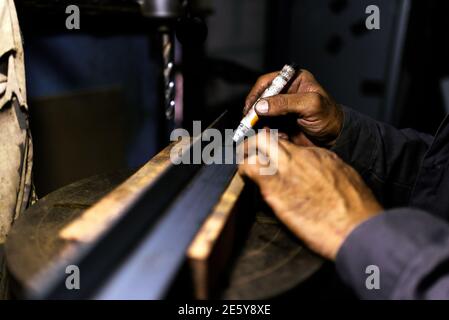 Stock photo of anonymous worker using drilling machine for metal in his workshop. Stock Photo
