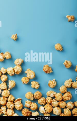 Popcorn is scattered on a blue background, in the form of a frame. Yummy for the filming of movies, TV series, cartoons. Free space, top view Stock Photo