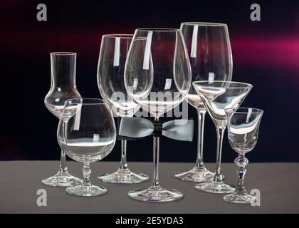Drinking glasses with bow tie isolated on black background. World Bartender Day. Stock Photo