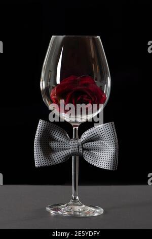 Wine glass with bow tie isolated on black background. International Bartender Day. Stock Photo