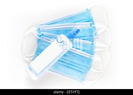 Desinfection spray and blue medical protective masks on white background. Covid-19, virus and bacteria protection. Stock Photo