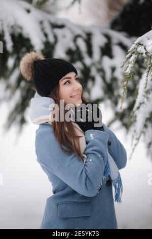 Pretty woman in blue coat walking in the woods on a winter snowy day. Beautiful woman posing to photographer Stock Photo