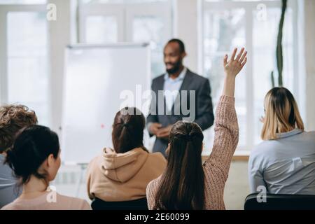 Focus on student. Male speaker giving presentation in hall at university workshop. Audience or conference hall. Rear view of unrecognized participants. Scientific, business event, training. Education Stock Photo