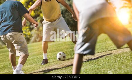 Group of Men Playing Soccer in park during lockdown with lens flare Stock Photo
