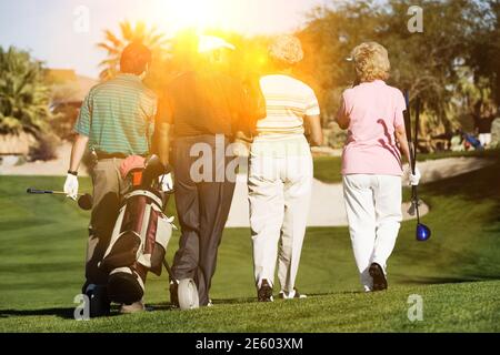 Rear view of senior golfers walking on the golf course Stock Photo