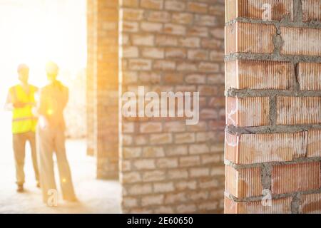 Blurred architect and construction manager at site with focus on brick walls Stock Photo