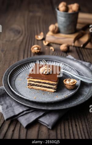 Gerbeaud bars filled with plum marmalade and crushed walnuts, topped with chocolate frosting on wooden background Stock Photo